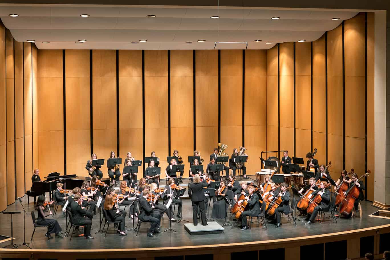 A stage is full of youth orchestra members playing their instruments