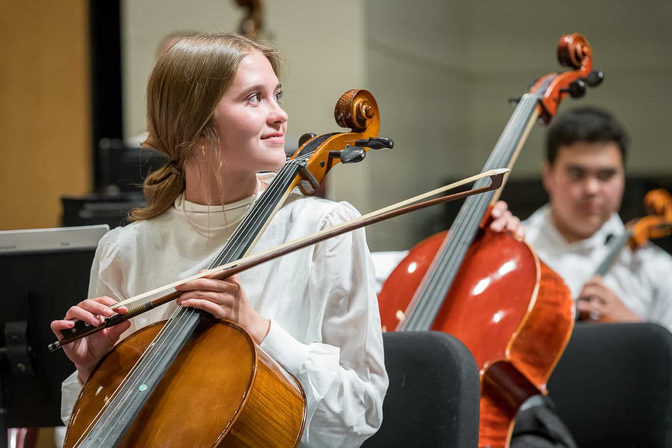 two youth cellists hold their instruments