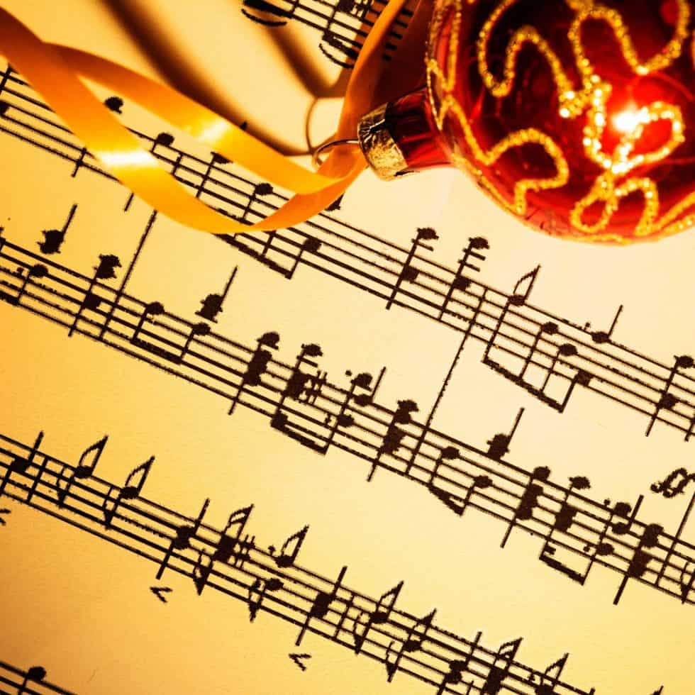 a page of music with a red Christmas ornament laying on it
