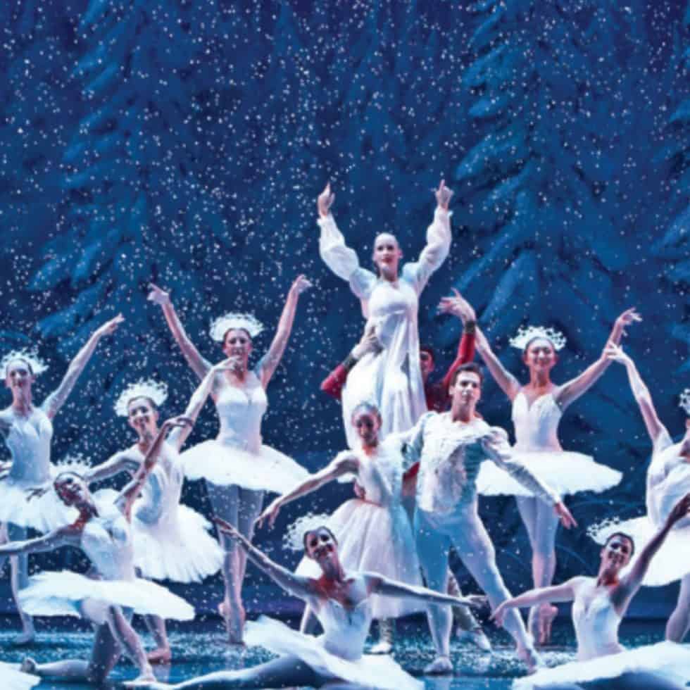 A group of Nutcracker ballet dancers all wearing white in a winter scene